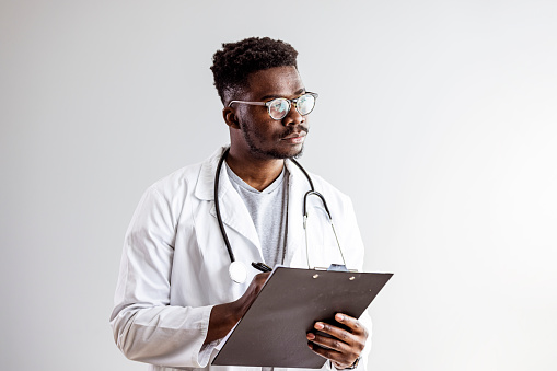 Portrait Of Mature Male Doctor Wearing White Coat Standing In Hospital Corridor. Male Doctor With Stethoscope Wearing White Coat Standing In Modern Hospital Building