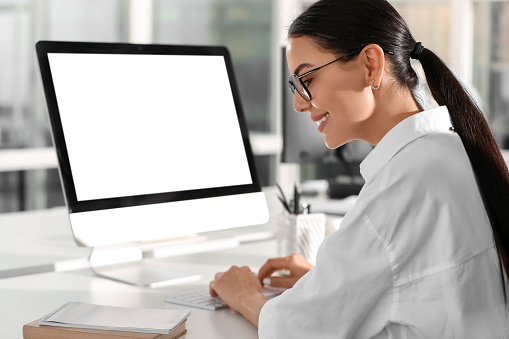 Happy woman using modern computer at white desk in office