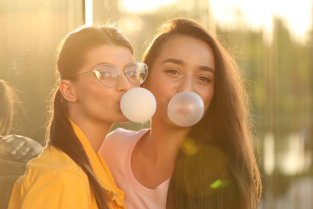 istock Beautiful young women blowing bubble gums outdoors on sunny day 1903213830