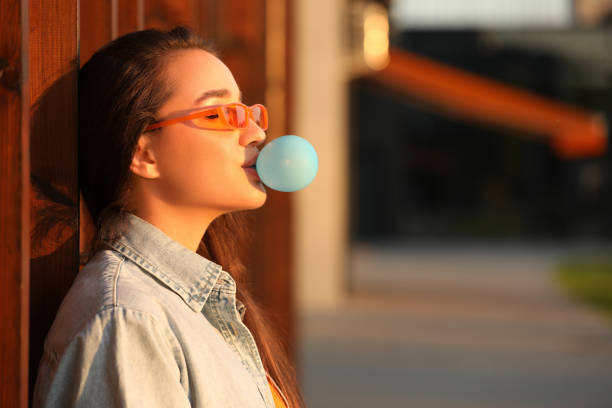 istock Beautiful young woman in sunglasses blowing bubble gum outdoors. Space for text 1903216943