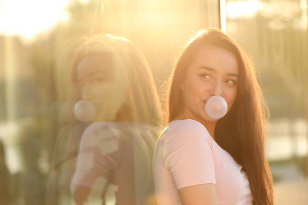 istock Beautiful young woman blowing bubble gum outdoors on sunny day. Space for text 1903217454