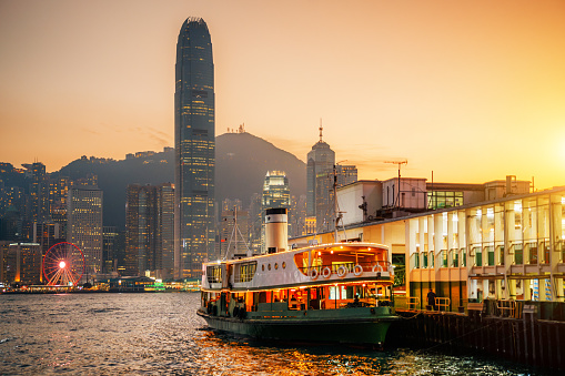 Victoria Harbor in Hong Kong paints a mesmerizing scene, the silhouette of a ferry boat adding charm to the city's twilight beauty.