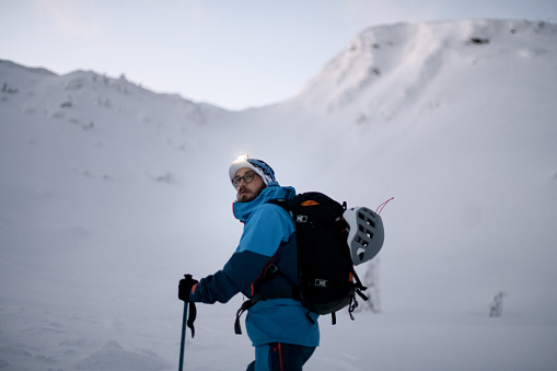 Male skier in bright jacket is climbing the hill using skitour equipment. Ski touring with amazing view of mountains