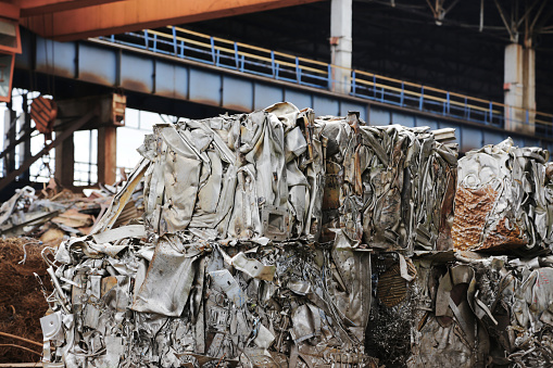 Scrap metal warehouse, pressing non-ferrous metal scrap into cubes. Pressed aluminum waste.