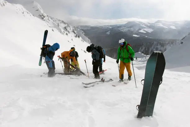 group of tourists high in the snowy mountains pour ski equipment splitboards. Winter activities, skitouring in mountains.