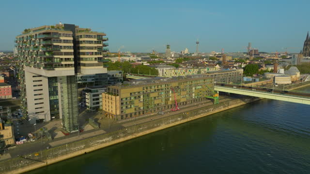Germany, Cologne. Aerial view of building with glass facade standing on waterfront. Reflection of surroundings and sunshine.