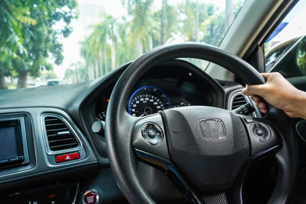 istock Male hand holding car steering wheel and car dashboard view 1903390216
