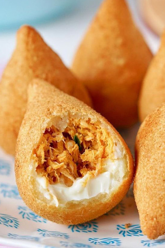The coxinha is a Brazilian savory, of São Paulo origin, made with wheat flour dough and chicken broth, which involves a filling made with seasoned chicken meat, cheese, pepperoni or several other types of flavors.