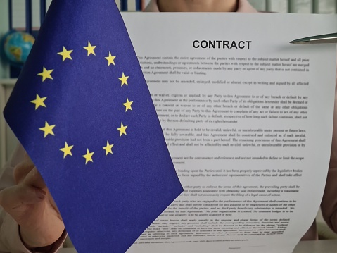 International contract with pen, European Union flag with office worker. Work and business in Europe