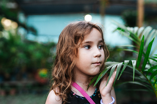 Portrait of a curious little girl in the plant garden