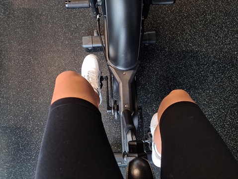 Sportswoman rides an orbitrek bicycle in gym top view. Sports fitness health