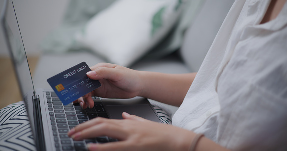 Close up hands of woman using laptop shopping purchasing online, typing digit, entering information, checking balance, browsing internet banking service, paying by credit card, online payment concept