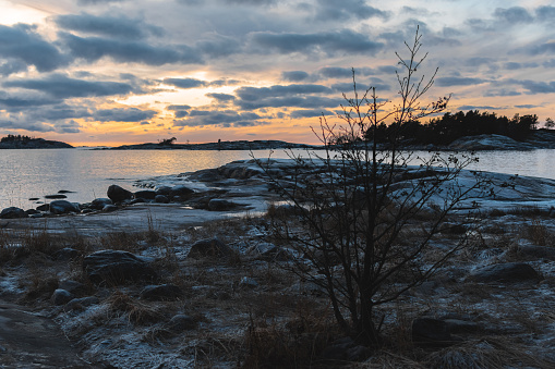 beautiful yellow sunset, cloudy sky, rocky coast in Helsinki, Uusimaa, Finland