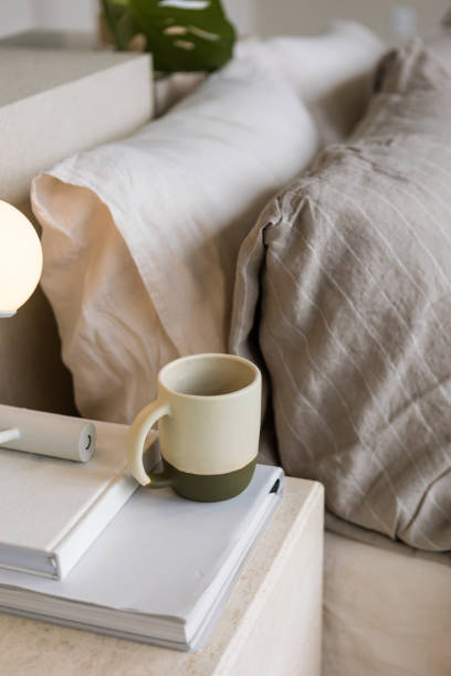 istock Ceramic mug atop books by an aesthetic bed creates tranquil scene 1903587588