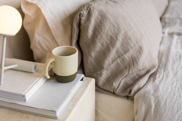 istock Ceramic mug atop books by an aesthetic bed creates tranquil scene 1903587891
