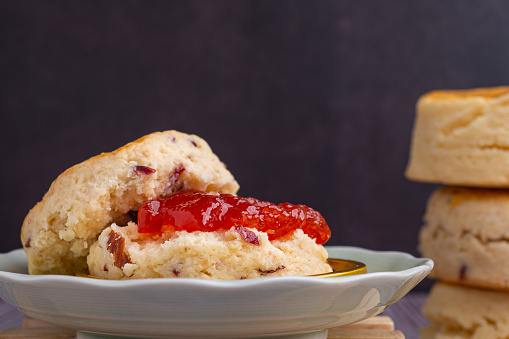 Scones traditional are delicious, freshly baked, and homemade, with strawberry jam on a wooden tray.