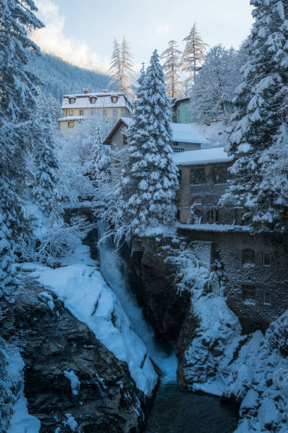 istock Fairytale snowy winter scene with waterfalls, trees and buildings 1903601241