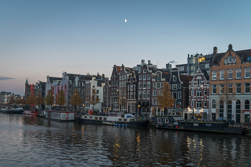 Morning half moon over Amsterdam canal and houses in Amsterdam, North Holland, Netherlands
