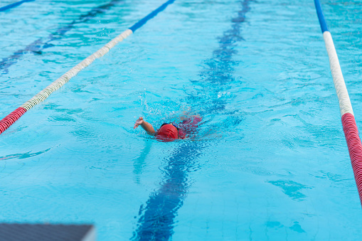 child swimmer swim in swimming pool. Water sports and competition, learning to swim classes for children.