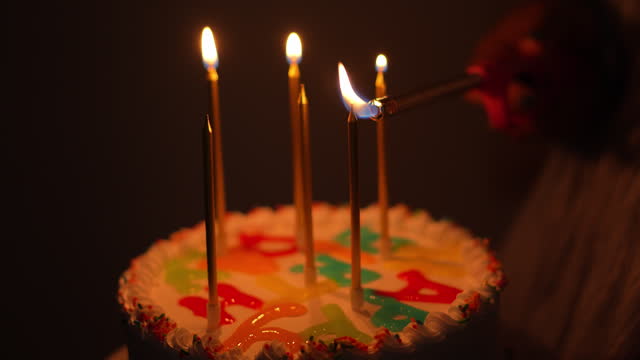 CU lighting candle on birthday cake.