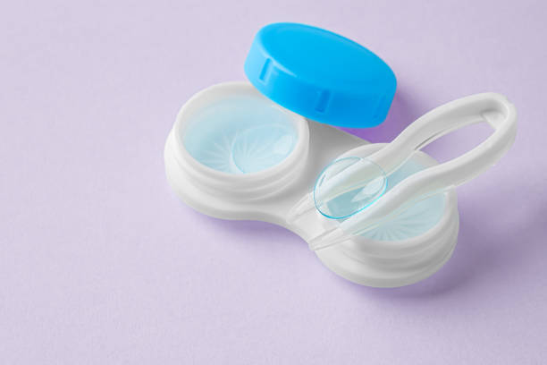 istock Contact lens on tweezer with solution liquid in case on pastel purple background 1903741501