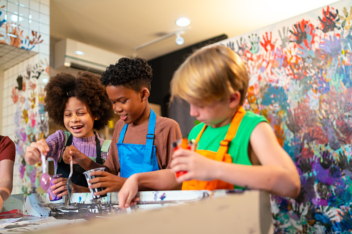 Group of Diversity school children learning acrylic art together in art class.