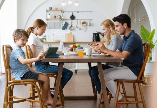 istock Father and Mother using smartphones and children using digital tablet and mobile phone while having breakfast at table in the morning at home. Family Phubbing And Gadget Addiction Issue 1903820627