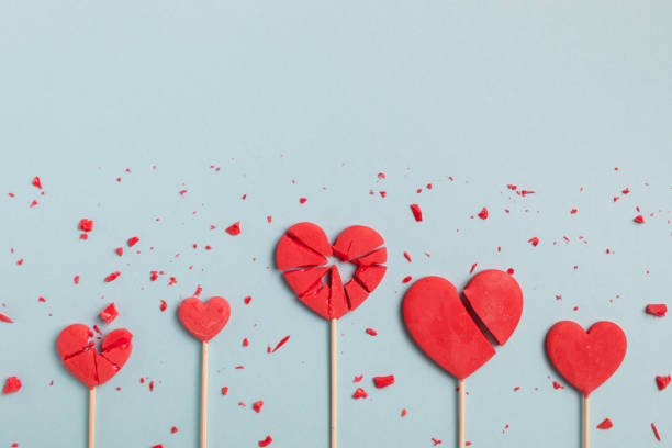 istock Valentine day concept with broken red lollipop hearts on pastel blue background top view. Flat lay greeting card. 1903906618