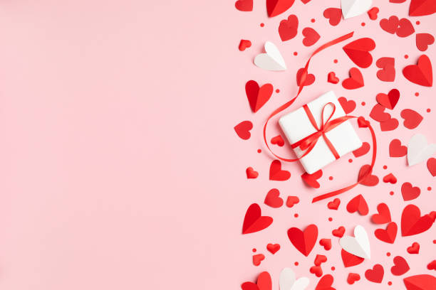 istock Valentine or Mother day festive border composition with gift or present box and many red hearts on pastel pink background top view. 1903911496