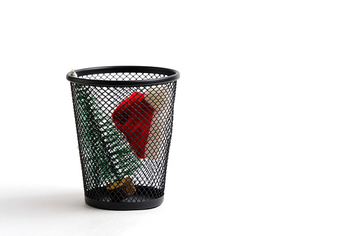 Christmas tree and Santa hat thrown in trash. Concept completing winter holidays