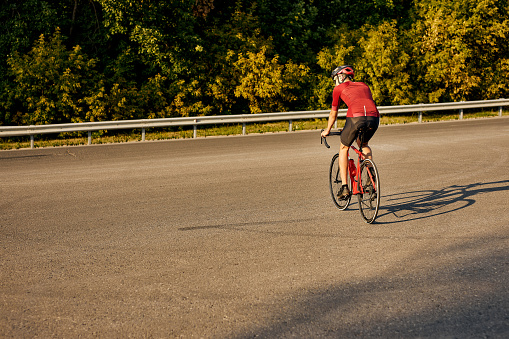 Rear view on young caucasian man wearing sport uniform and glasses riding great bike, going in for favorite activity. handsome guy in sportive outfit is engage in sport, healthy lifestyle