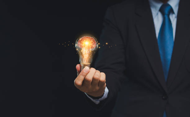 istock Close-up of hand a businessman holding a lighting bulb with lighting while standing on a black background 1903979505