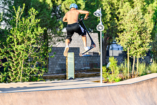 Igualada, Barcelona; June 25, 2023: Young man practicing Scootering (Freestyle Scootering) in the new SkatePark of the central park of Igualada, Barcelona, Spain