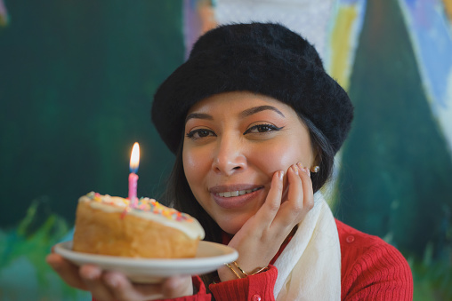 Mexican woman holding a dessert with a birthday candle.