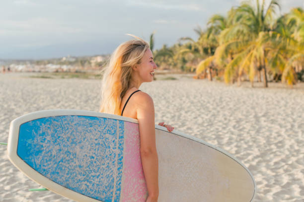 istock Cheerful woman with surfboard on beach 1904016063