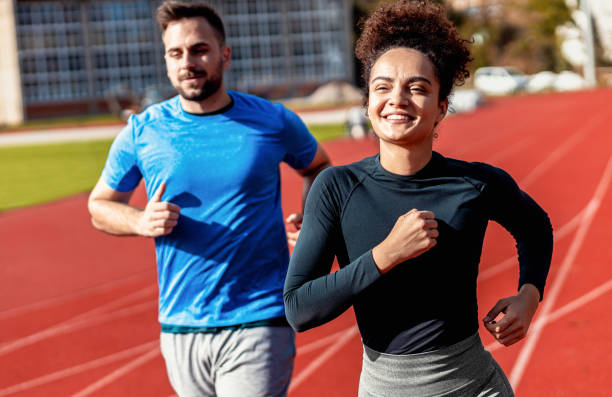 istock Woman and man doing morning workout outdoors running on track. 1904022383
