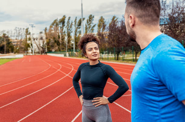 Smiling fitness couple stretching before morning workout on running track outdoors. stock photo