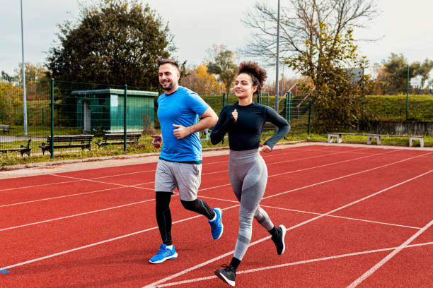 istock Woman and man doing morning workout outdoors running on track. 1904022919