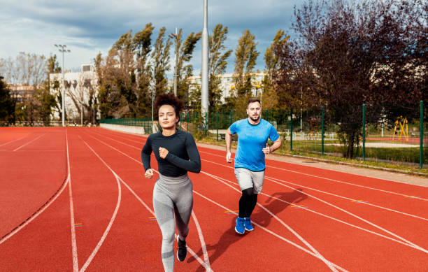 istock Woman and man doing morning workout outdoors running on track. 1904022928