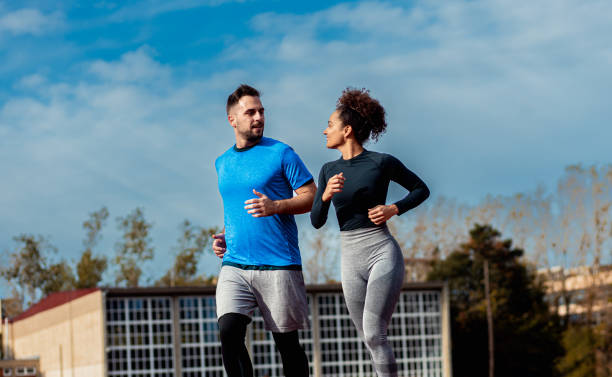 istock Woman and man doing morning workout outdoors running on track. 1904023436