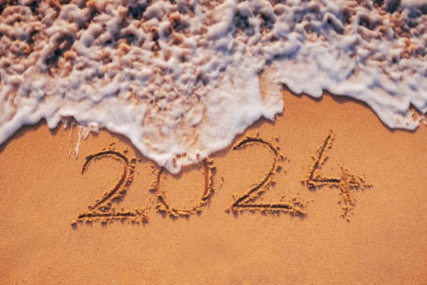 istock 2024 text in sea sand and curly wave on the beach nature background 1904045695
