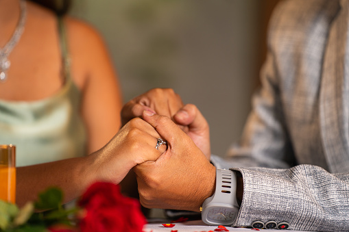 Close up shot, romantic man holding girlfriends or wifes hand during candlelight dinner - concept of intimacy, physical touch or connection and affectionate couples