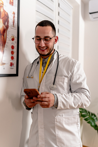 The doctor's commitment is evident as he actively uses his mobile phone in the office, staying connected with patients and peers