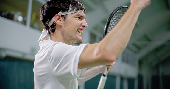 Young male tennis player being happy and smiling after succeeding tennis match.