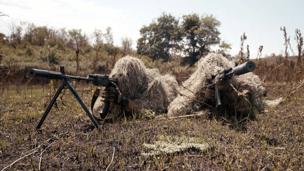 Snipers in an ambush in the grass, disguised as terrain on an anti-terrorist operation with sniper rifles, shooting at the enemy. Footage of military operations. Soldiers in full gear. Cinematic shot francotiradores en una emboscada en la hierba, disfrazados de terreno en una operación antiterrorista con rifles de francotirador, disparando al enemigo. imágenes de operaciones militares. soldados con equipo completo. plano cinematográfico