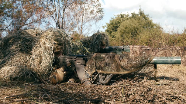 Snipers in an ambush in the grass, disguised as terrain on an anti-terrorist operation with sniper rifles, shooting at the enemy. Footage of military operations. Soldiers in full gear. Cinematic shot francotiradores en una emboscada en la hierba, disfrazados de terreno en una operación antiterrorista con rifles de francotirador, disparando al enemigo. imágenes de operaciones militares. soldados con equipo completo. plano cinematográfico