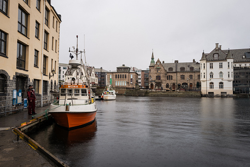 Alesund, Norway - November 1, 2023: Winter city scapes on November 1, 2023 in Alesund, Norway. City life in Alesund, with fishing boat in the canals of the harbor