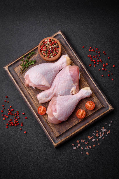 istock Raw chicken legs with salt, spices and herbs on a dark concrete background 1904163255