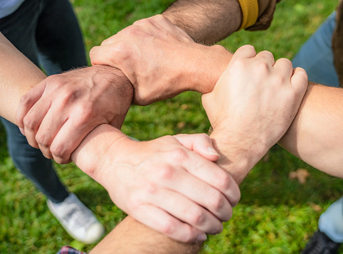 Close-up as four men each hold each other's arm, creating a strong bond.