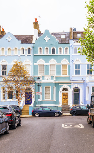 Large pastel coloured townhouses on a street in Notting Hill, in the Royal Borough of Kensington and Chelsea, London.